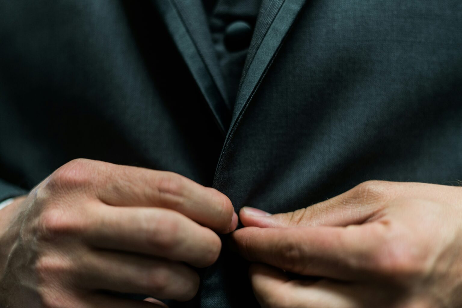 A business leader fastening the button of a tailored suit jacket