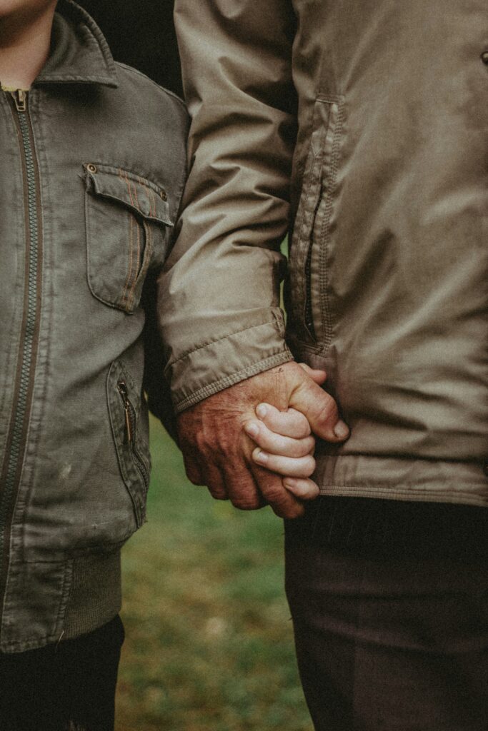 An older hand gently holding a child's hand